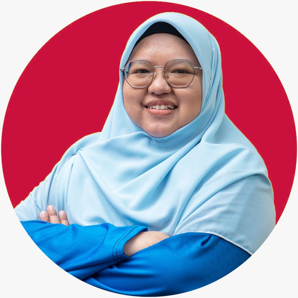 A woman in blue hijab and clothe smiling with red background at the back