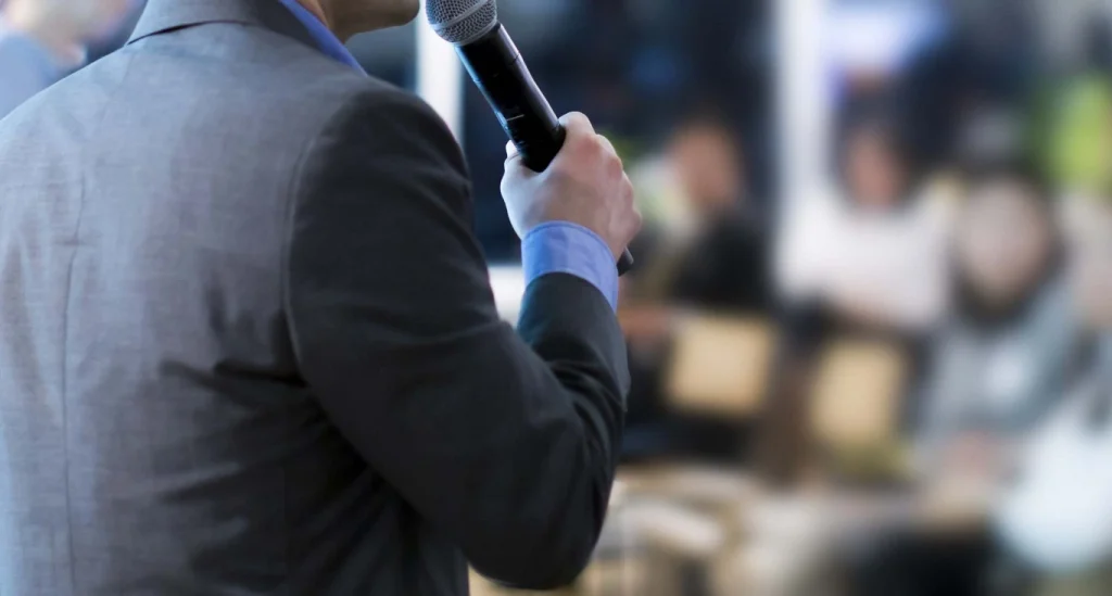 Pemimpin menyampaikan pembentangan sambil menunjukkan kemahiran komunikasi pemimpin kepada audiens.